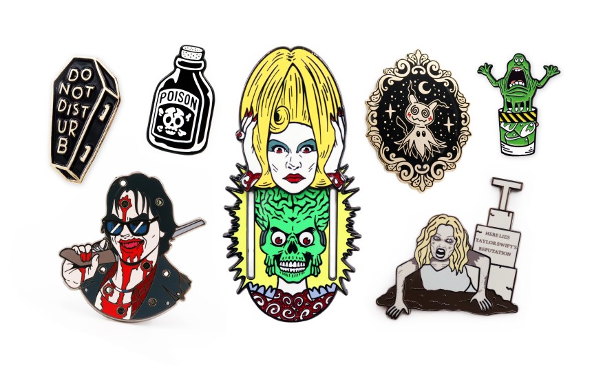 A collection of 7 horror pins badges from Mars Attacks, Taylor Swift's grave, Slimer from Ghost Busters, bottles of poison and a coffin.
