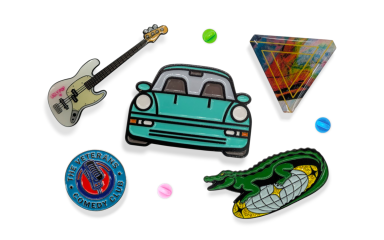 A selection of different styles of pin badges featuring a car, guitar, funky triangle, a crocodile on a disco ball, and a circular branding badge.