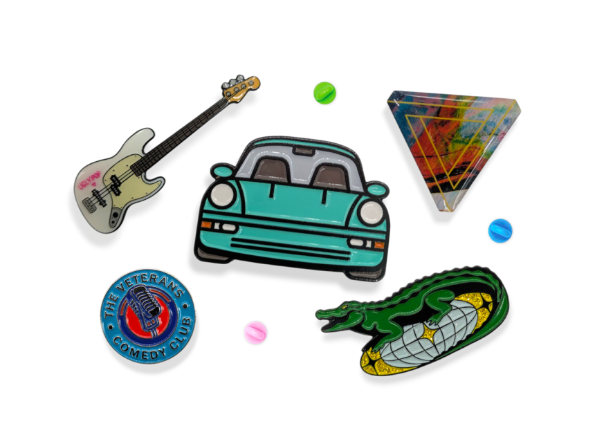 A selection of different styles of pin badges featuring a car, guitar, funky triangle, a crocodile on a disco ball, and a circular branding badge.