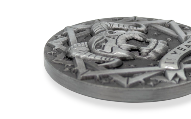 A close up of a custom challenge coin that shows the intricate details of a coin that has a satanic style design with a pentagram and horned skull.