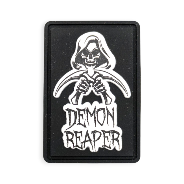 A black rectangular rubber patch with a picture of a grim reaper with the words