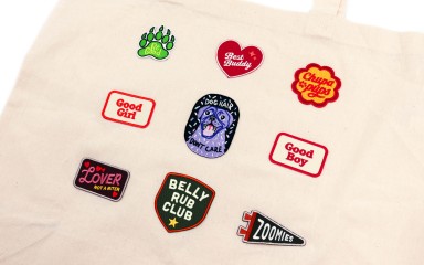 A tote bag with nine dog-related iron-on patches stuck down.