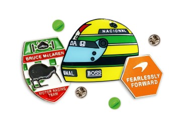 F1 Custom Merch - An Aryton Senna vintage f1 helmet pin badge, a Bruce McLaren long service award badge, and McLaren's Fearlessly Forward branding enamel pin.