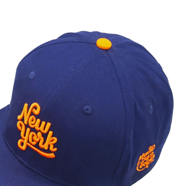 Navy custom baseball cap featuring orange New York embroidery and top button, highlighting high quality custom snap backs with bold detailing.
