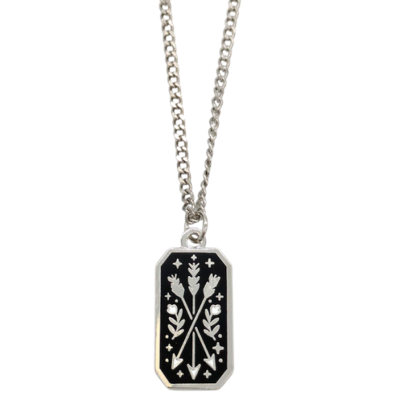 A rectangular silver-plated pendant with a black background with three silver arrows, with flowers and stars surrounding it.