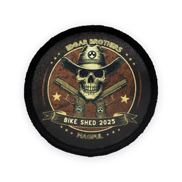 Round printed patch featuring a skull wearing a cowboy hat with crossed guns, Edgar Brothers branding and “Bike Shed 2025 Magpul” text, printed in vintage tones with a stitched black border for event or promotional use.