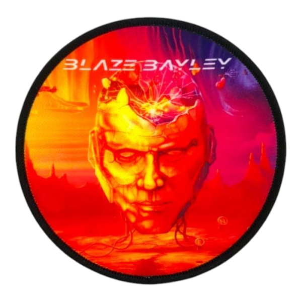 A circular printed patch with black overlocked edge. The photo-realistic image of an orange head floating over the sea of stix, with the name