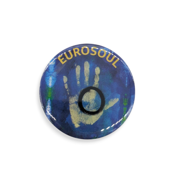 A circular printed pin badge featuring a yellow handprint with a black circle on it. The words