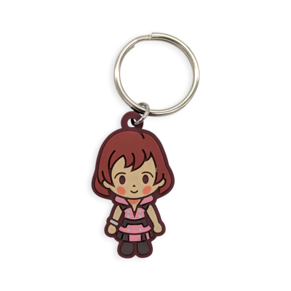 A rubber keychain featuring a cartoon child with a cute face and brown hair.