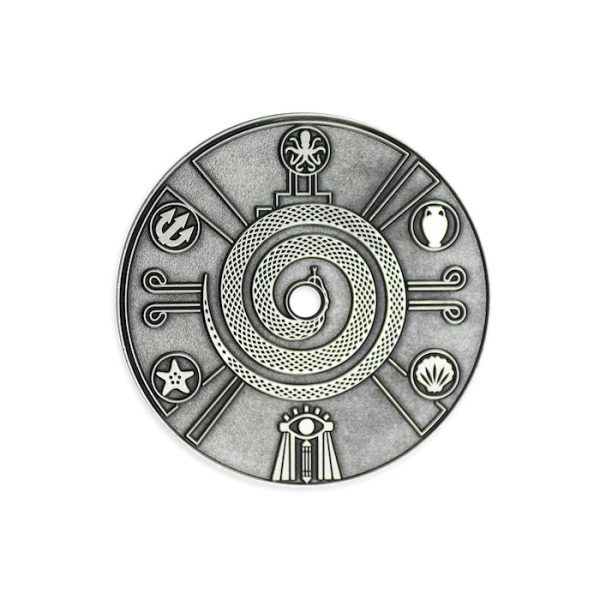 An antiqued silver-plated coin featuring Eygptian icons and drawings around the outside of a curled up snake.