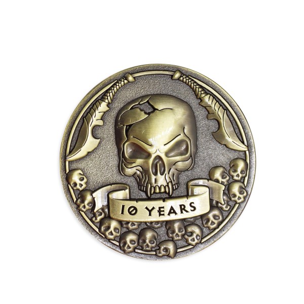 A 1 sided custom coin with a menacing looking skull flanked by two knives. A banner underneath the skull reads