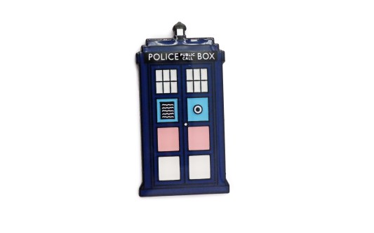 A pin badge of Doctor Who's TARDIS using the trans rights flag colours.
