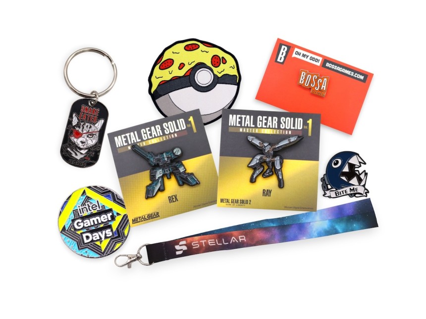 Video game pins and gaming merch including enamel pins, keyrings, lanyards and socks displayed together from some of the biggest names in the industry like Konami, Intel, Pokemon, Nintendo, and Bossa Games.