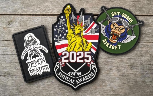 Collection of custom PVC patches including awards badge, airsoft logo and reaper design with vibrant colours and raised detailing.