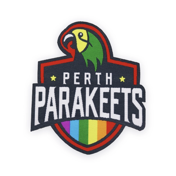 Shield shaped woven patch with Perth Parakeets text, parrot graphic and rainbow stripes, created as a bold custom woven patch for sports teams, clubs or inclusive branded woven patches UK.